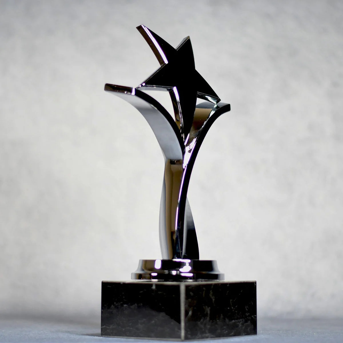 TWISTING STAR ON BLACK MARBLE BASE, GOLD, SILVER, BRONZE