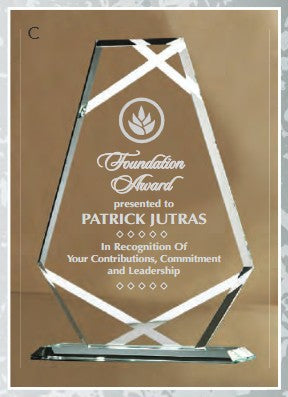 Glass award with engraved text on a brown background