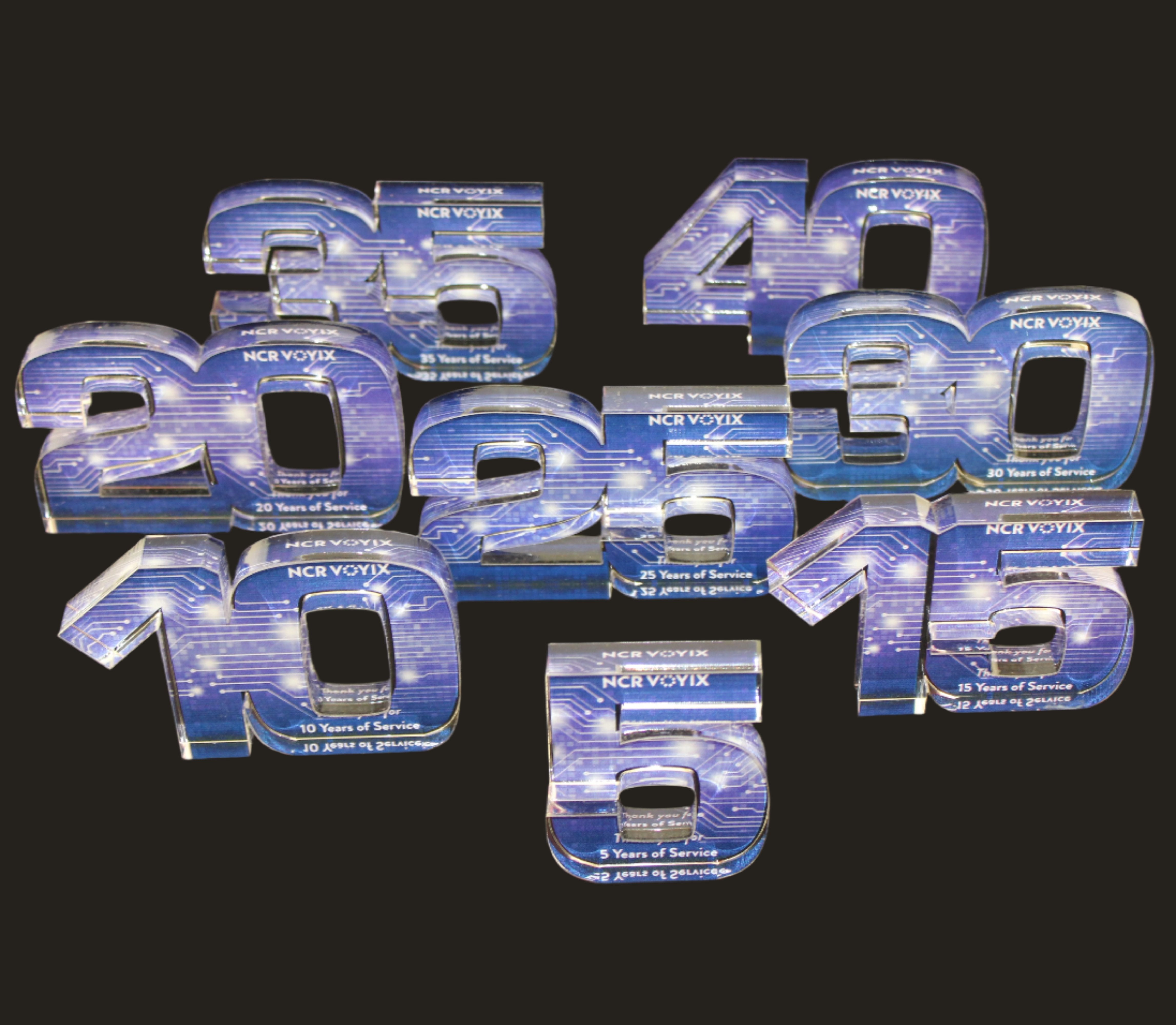 A collection of acrylic awards in the shape of numbers, representing years, arranged in a collage format.