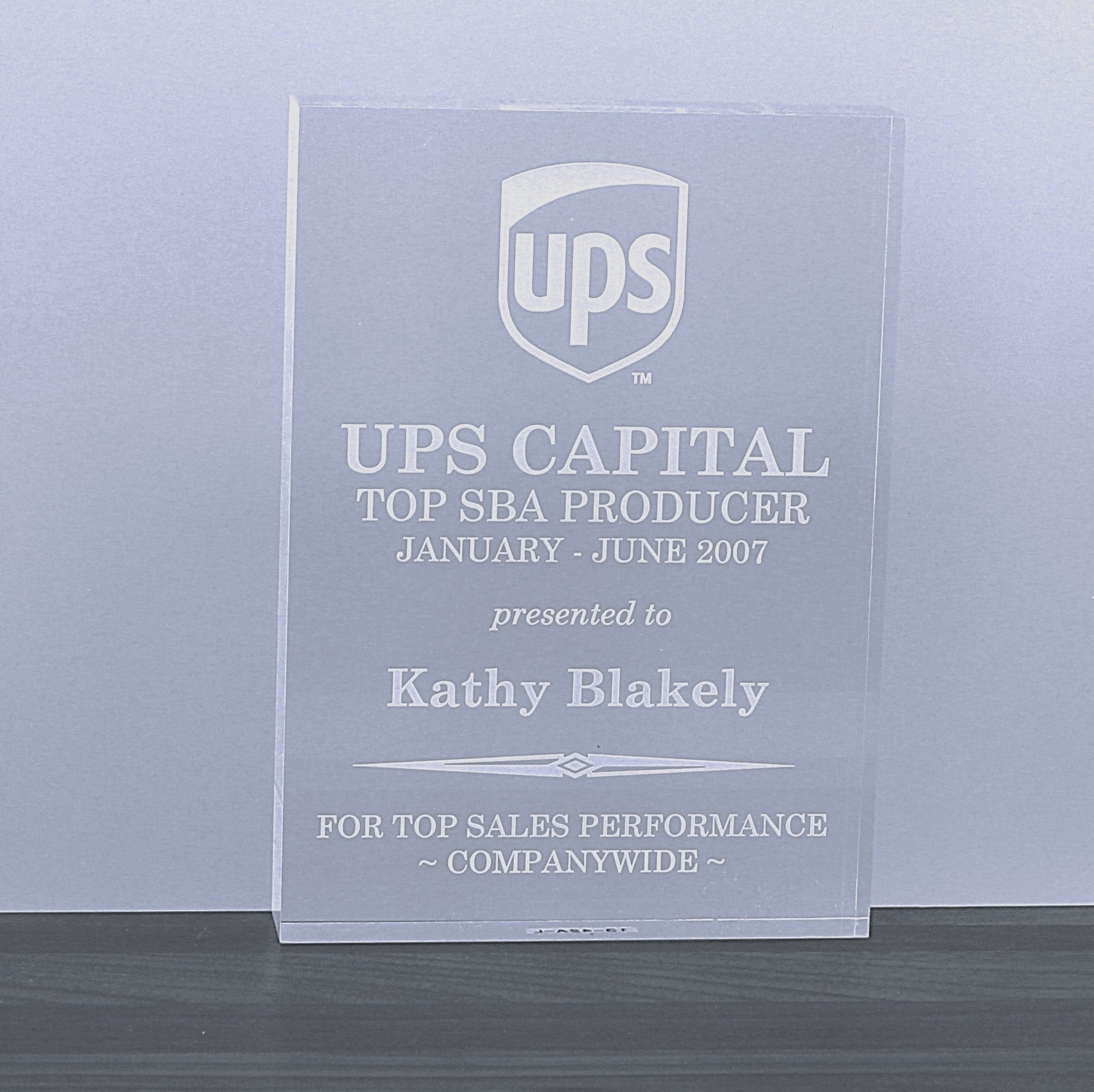 An acrylic rectangle block award with a logo and the text 'Top Producer with dates alongside a personalized greeting
