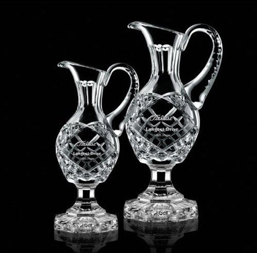 Two clear crystal footed pitchers with geometric patterns, one larger than the other, displayed against a black background.