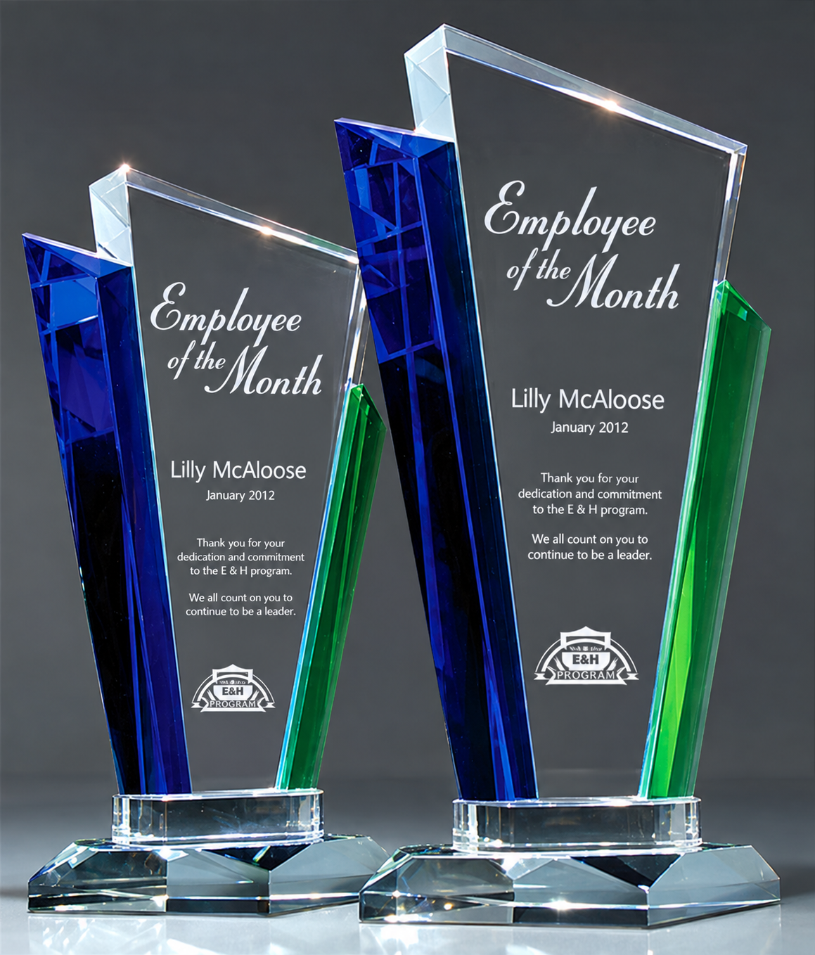 Two custom crystal award features blue and green triangular accents, both with clear rectangular acrylic towers and bases.