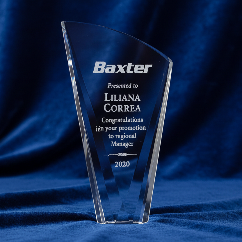 Clear glass award with engraved text on a blue fabric background