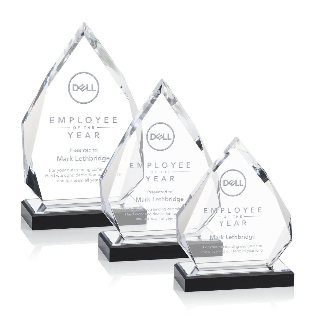 A set of three clear glass awards with diamond-like facets, featuring engraved text and the Home Depot logo, presented on a black surface.