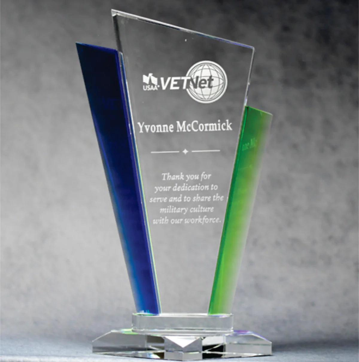 Optic crystal palace award with blue and green accents, standing at different angles, displaying engravings on their surfaces.