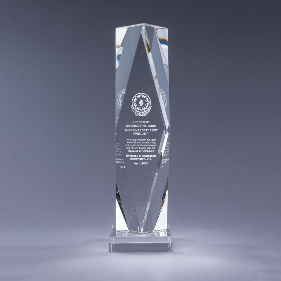 Clear glass award with clear crystal base and engraved text on a gray bbackground