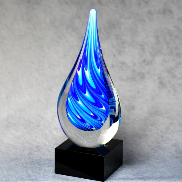 A blue and white swirl teardrop-shaped art glass award mounted on a black glass base, with a laser engraveable aluminum plate.