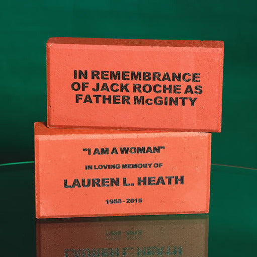 Two red laser-engraved bricks with a message in memory as a tribute and a dedication