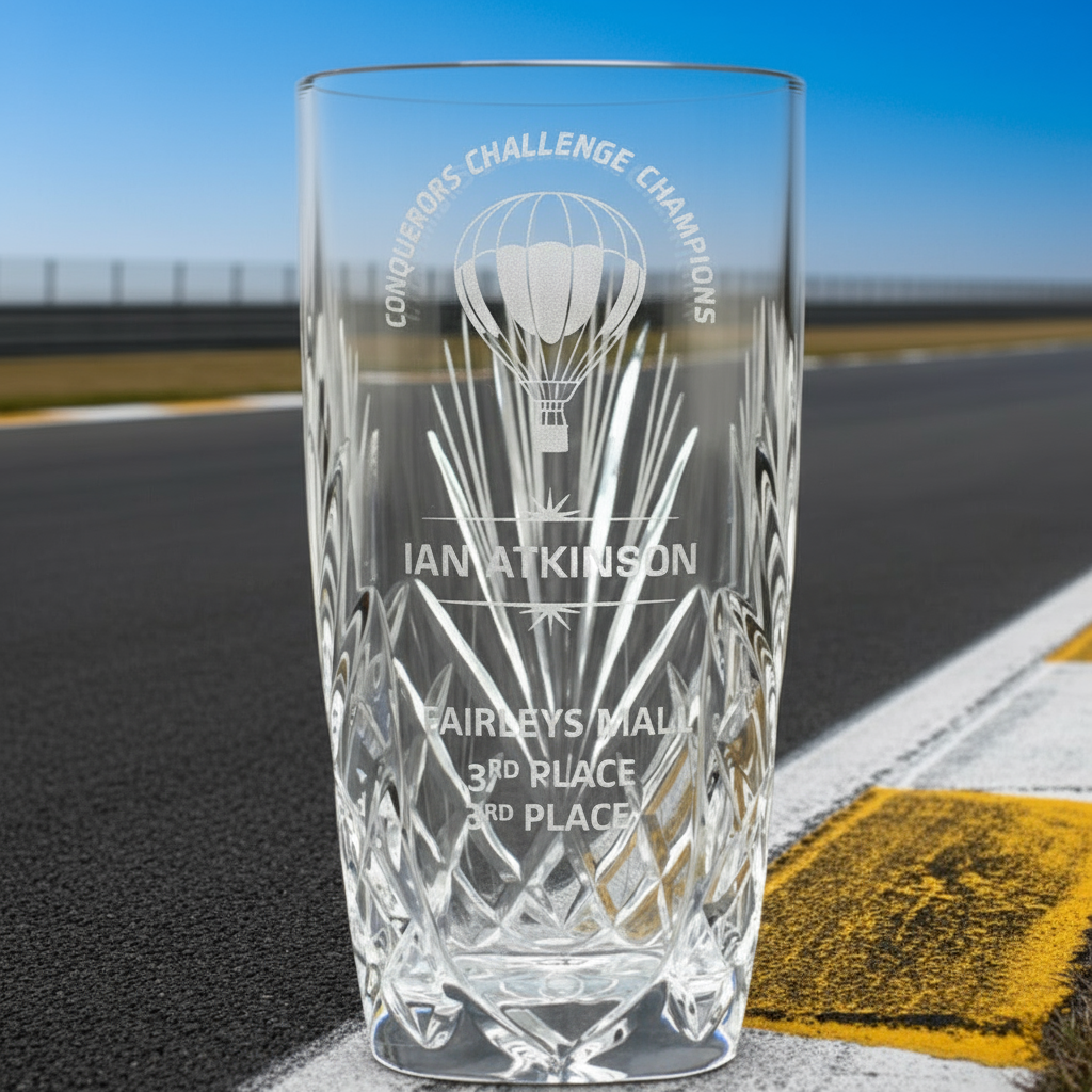 Clear glass engraved vase with text and a logo on a race track background