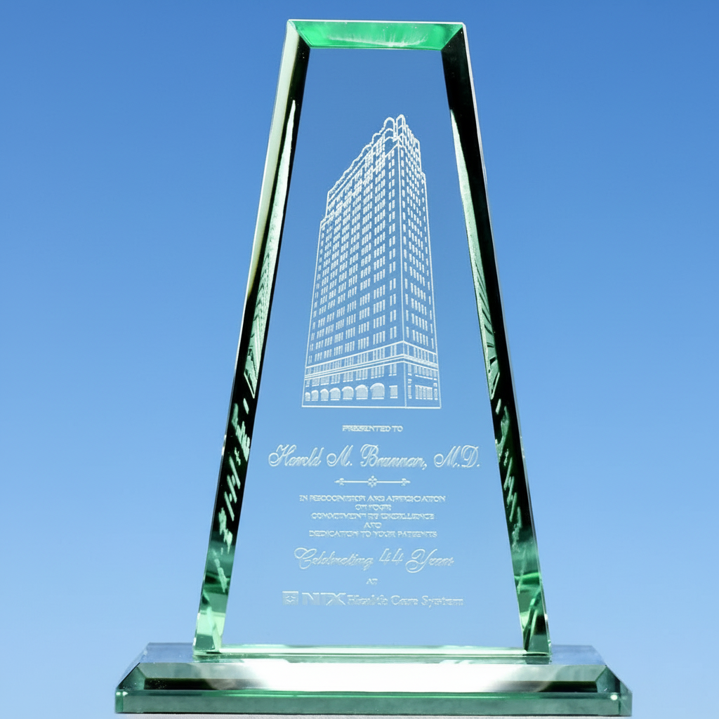 Green glass award with engraved building design on a blue background
