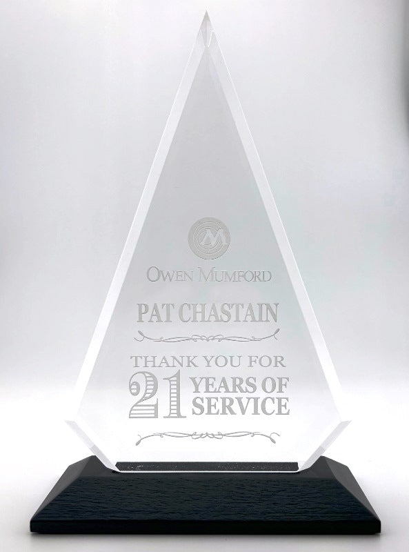 Triangular glass award with engraved text on a white background