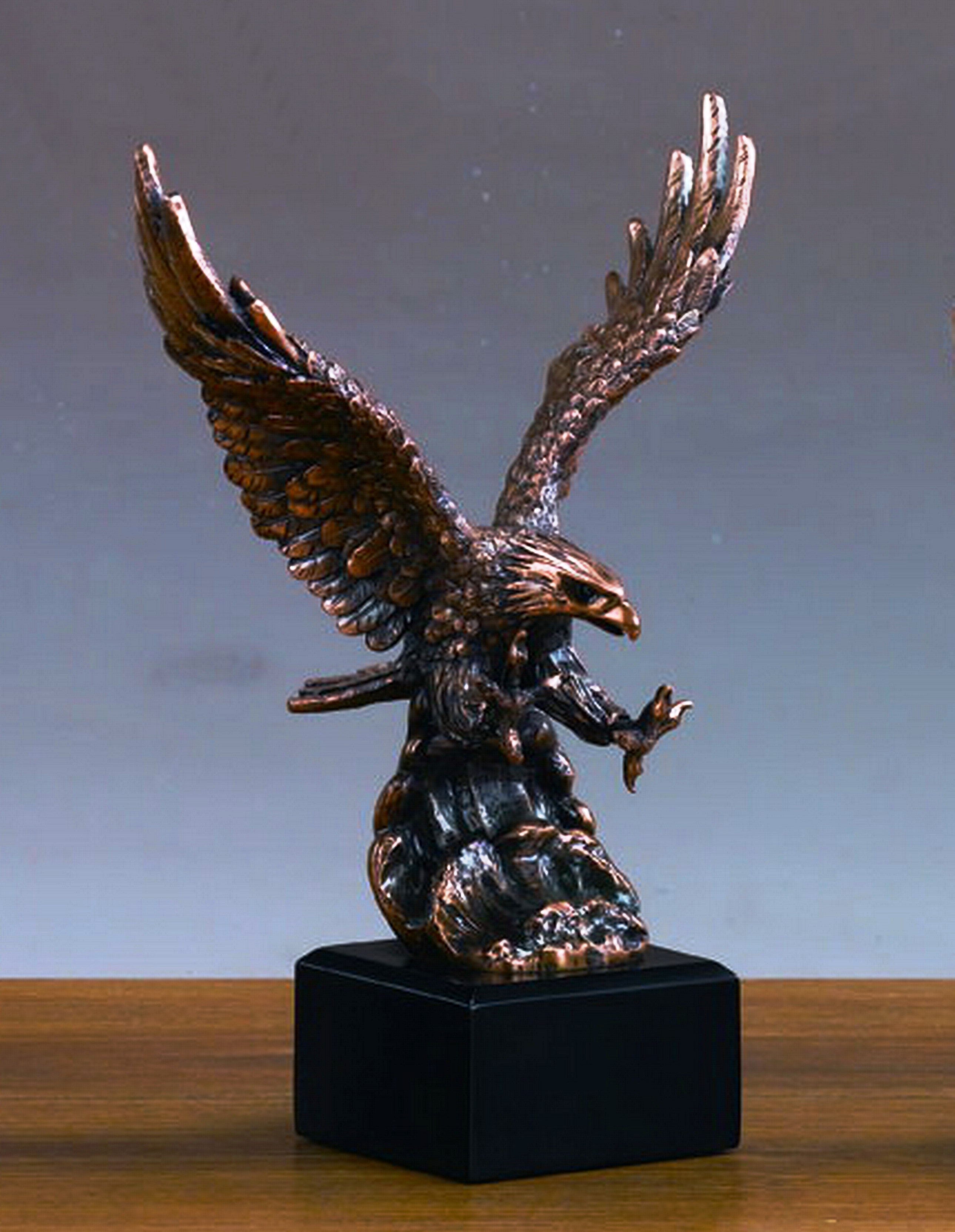 Bronze eagle sculpture on a black base against a gray background