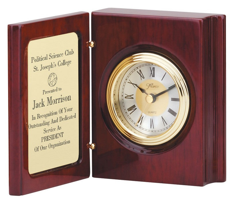 A rosewood book clock with a brass engraving plate, presented as a personalized award. The interior of the book features a clock with Roman numerals and a wooden finish.
