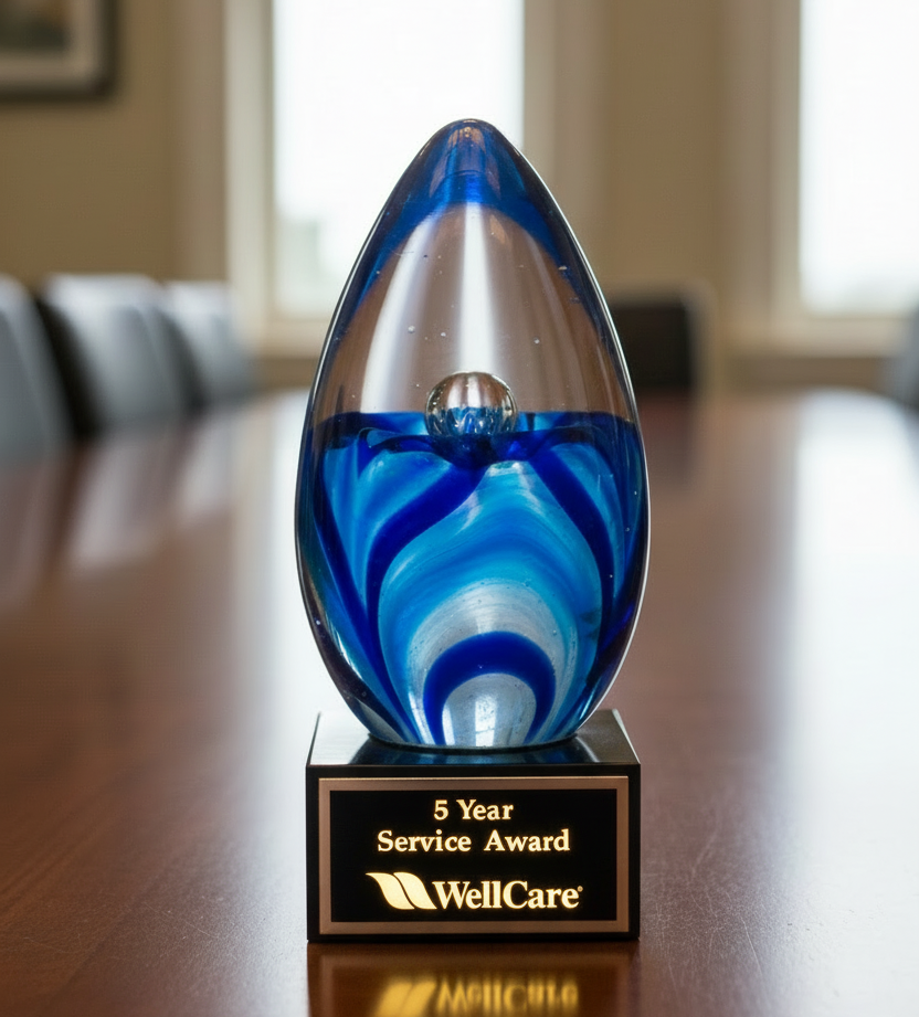 Blue and silver glass award on a wooden table with 'WellCare' branding