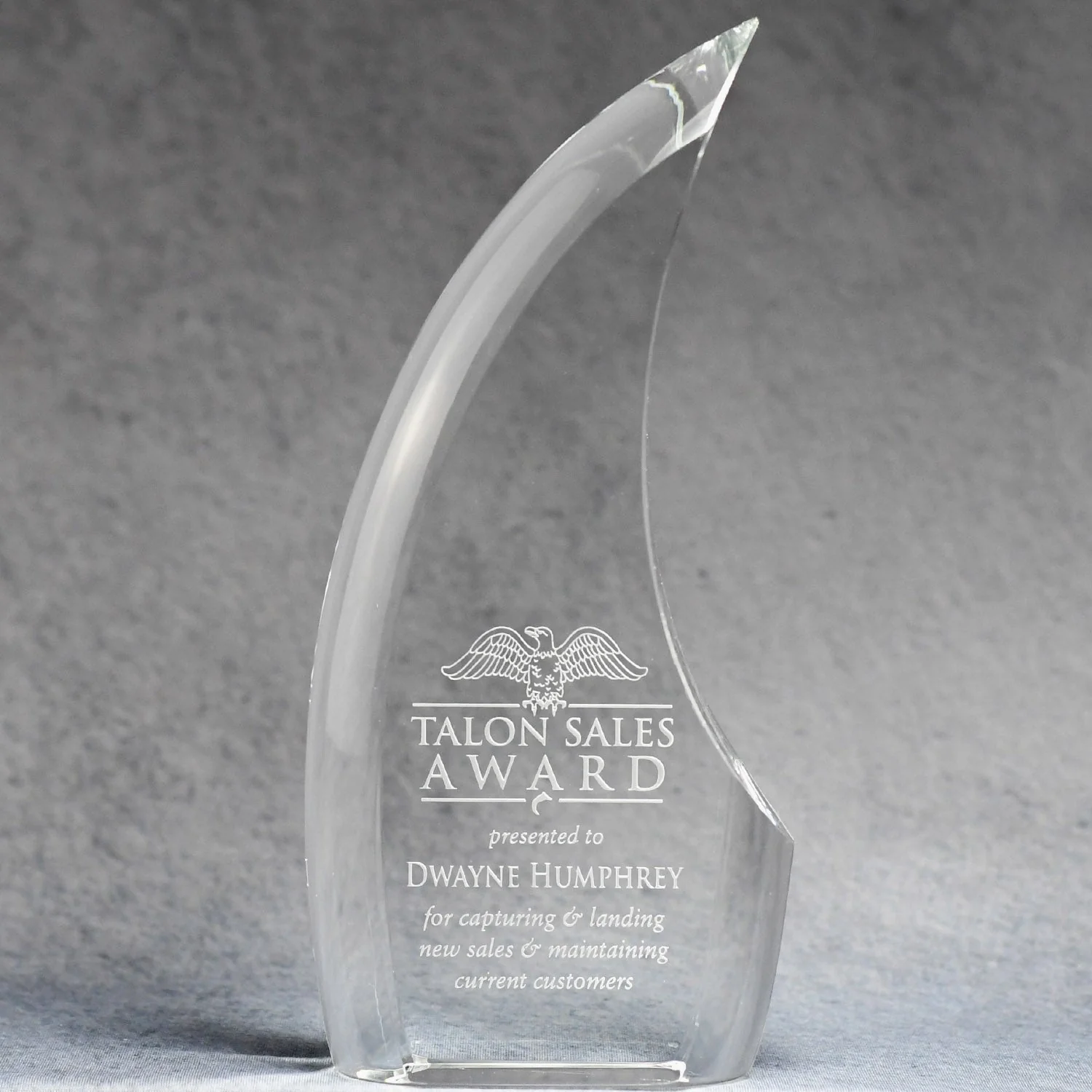Crystal award with engraved text on a gray background