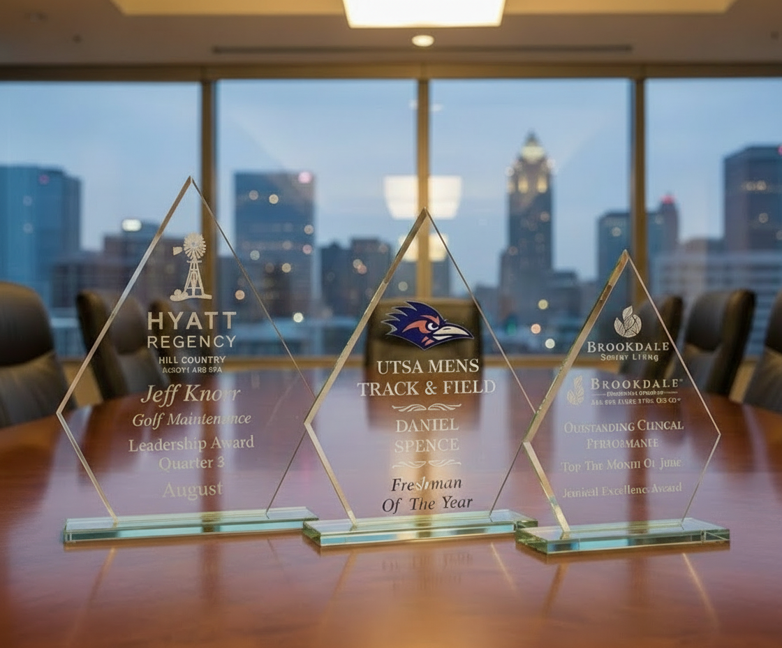 Three glass awards on a table with a cityscape in the background