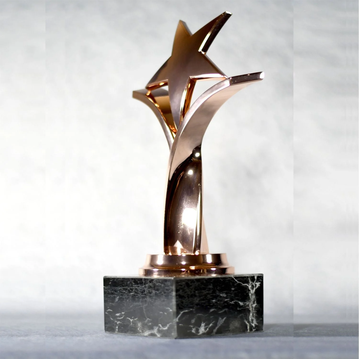 TWISTING STAR ON BLACK MARBLE BASE, GOLD, SILVER, BRONZE