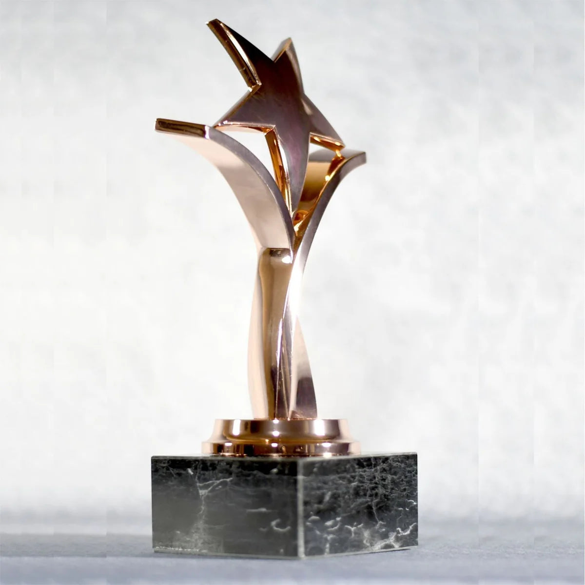 TWISTING STAR ON BLACK MARBLE BASE, GOLD, SILVER, BRONZE