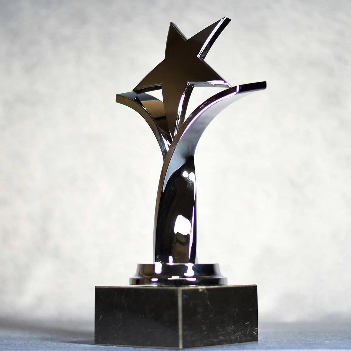 TWISTING STAR ON BLACK MARBLE BASE, GOLD, SILVER, BRONZE