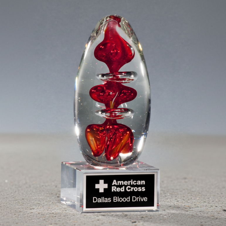 Crystal sculpture with red interior on a gray background, featuring American Red Cross Dallas Blood Drive label.