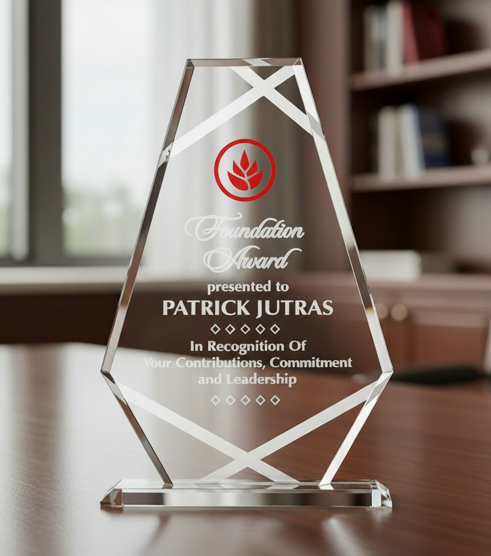 Glass award with engraved text and logo on a wooden surface