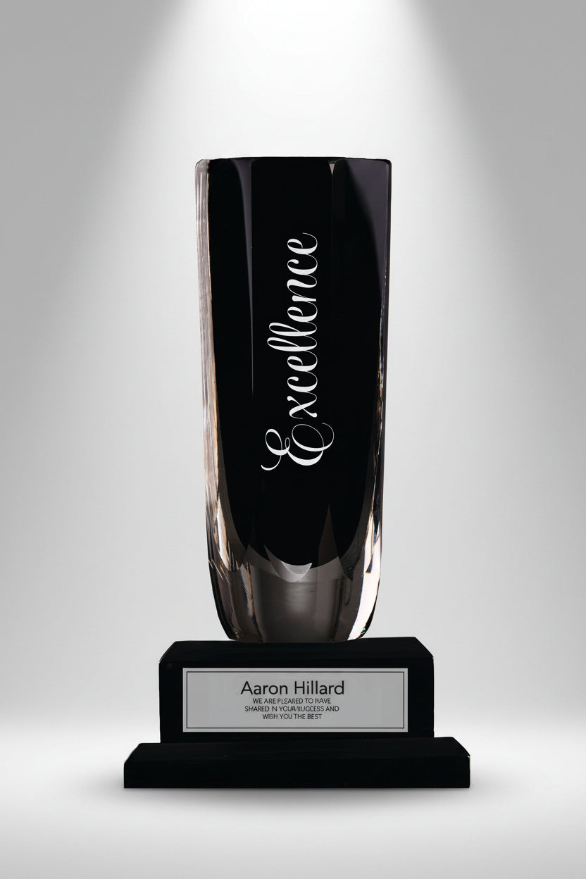 Tall black and glass trophy with 'Excellence' engraved on a white background