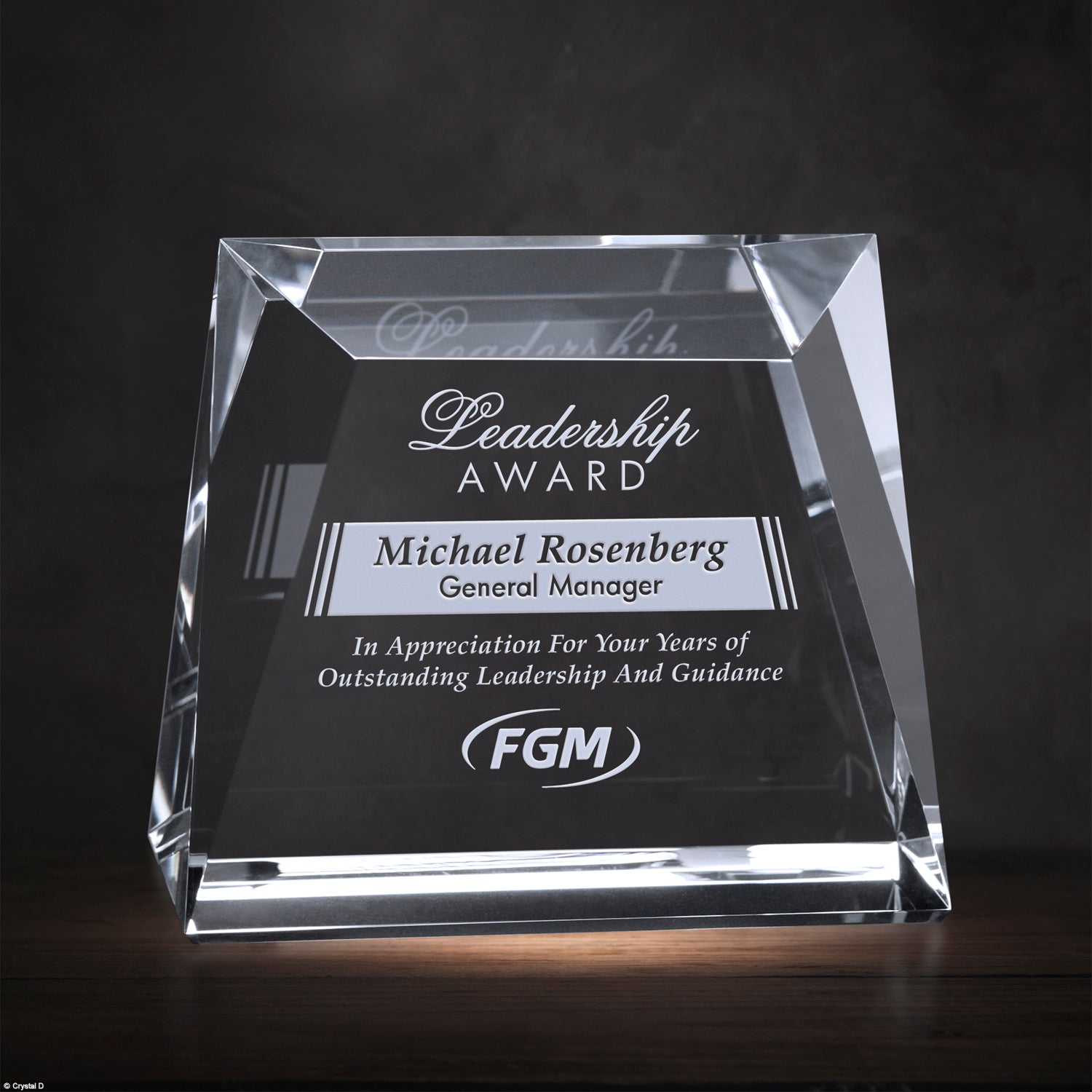 Crystal leadership award with engraved text on a dark background