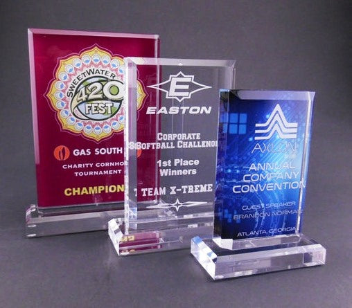 Three acrylic awards with different logos and text 