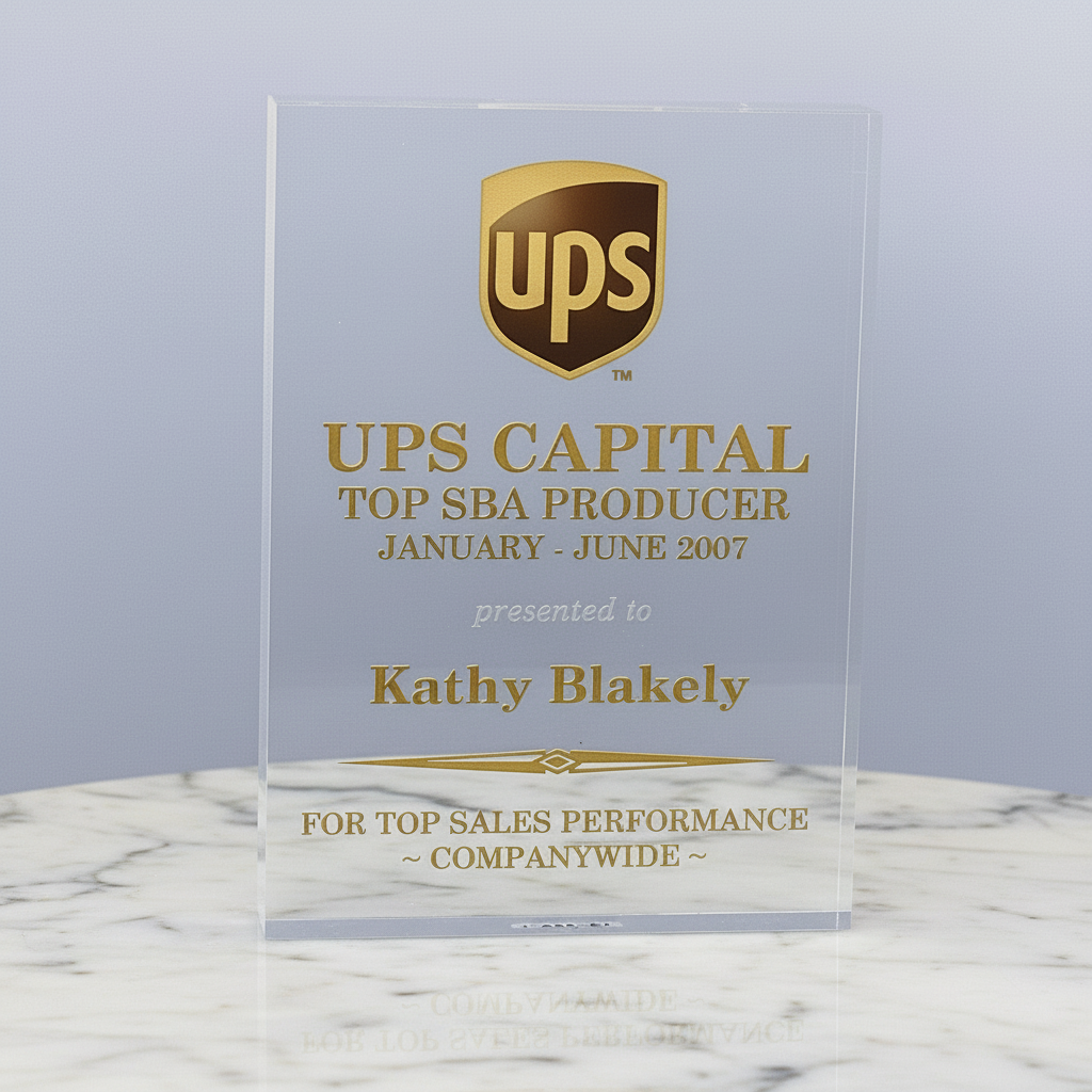 Acrylic award with UPS Capital logo and text on a marble surface