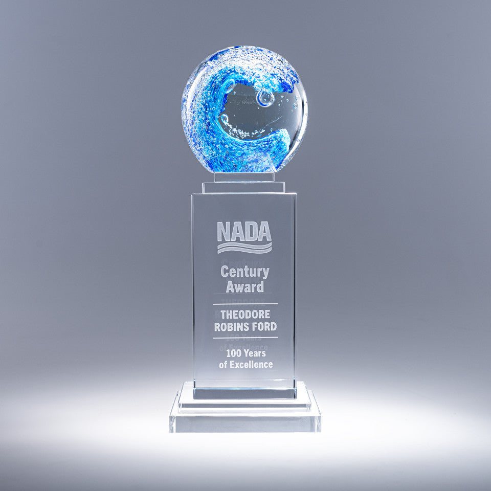 Glass award with blue globe and engraved text on a gray background