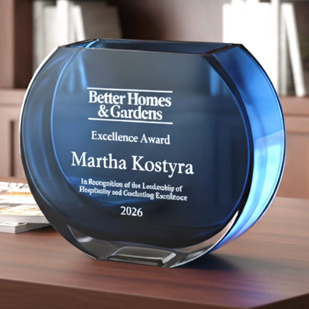 Blue glass award with 'Better Homes & Gardens' and 'Martha Kostyra' engraved on a wooden surface.