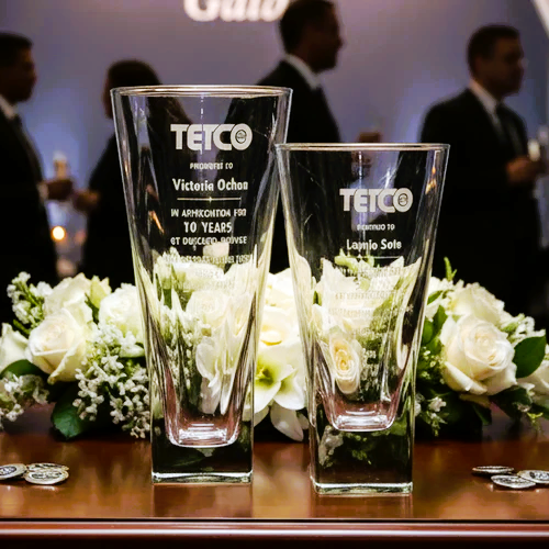 Two engraved glass vase awards at a corporate banquet.