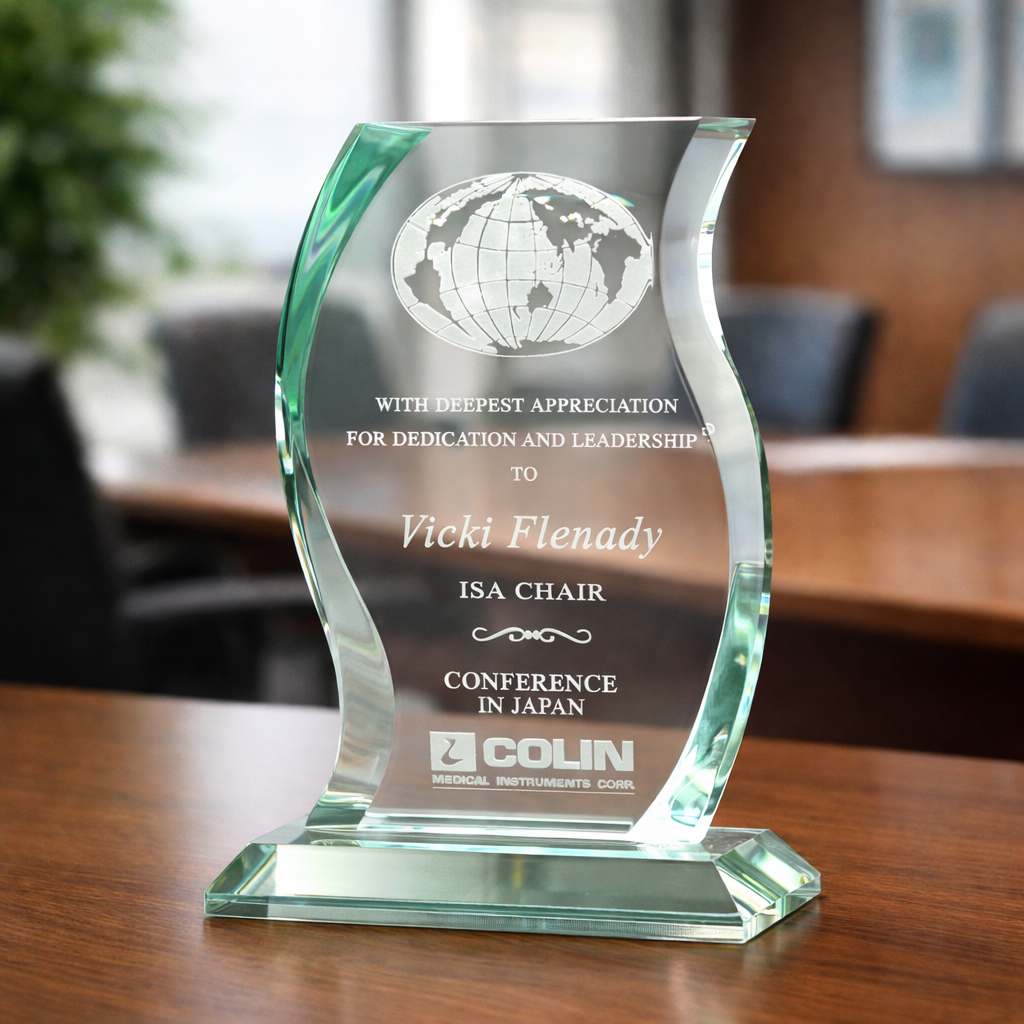 Glass award with engraved text on a wooden table