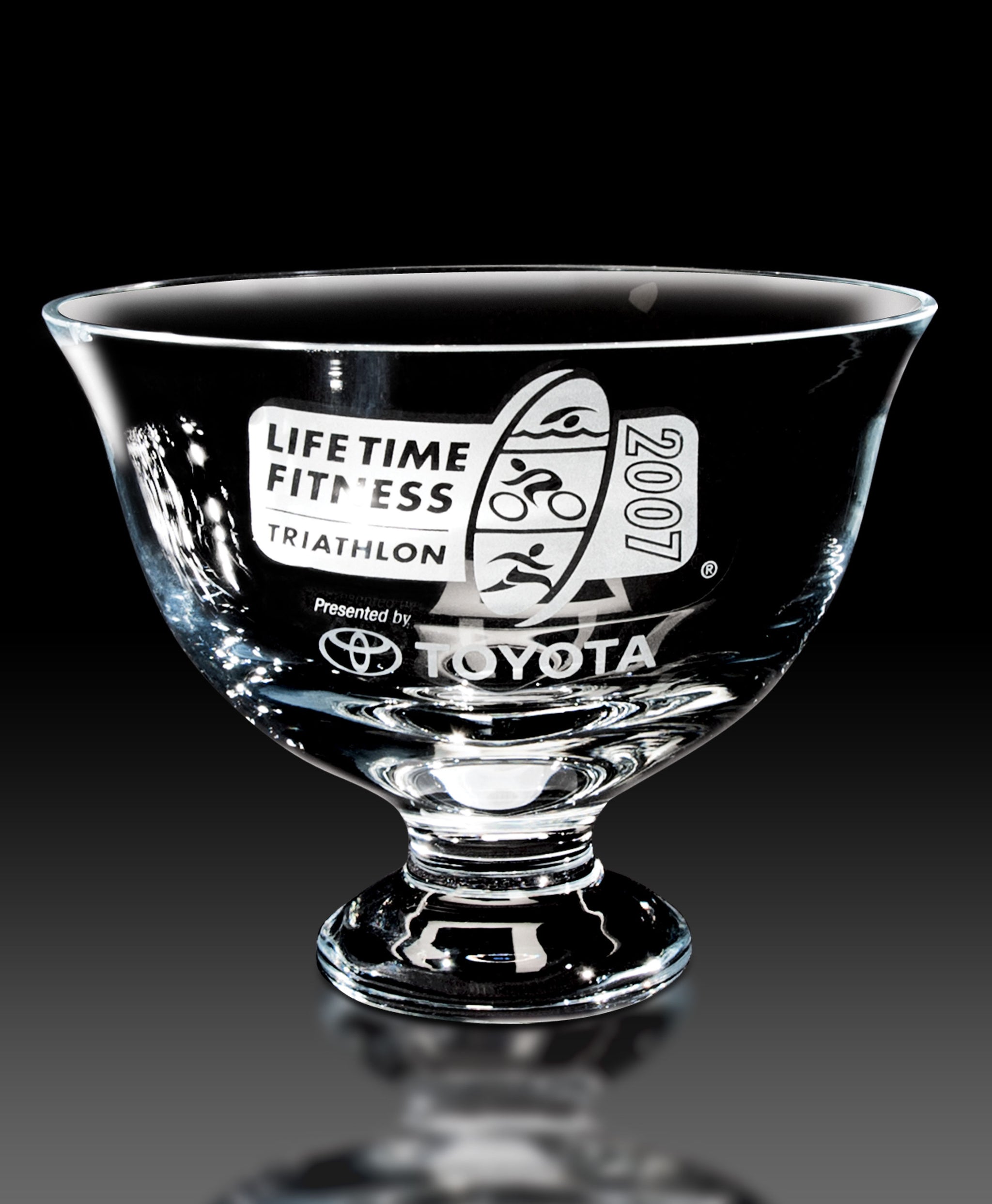 A clear crystal footed bowl with etched black text displaying 'Lifetime Fitness Triathlon' and other sponsor logos.