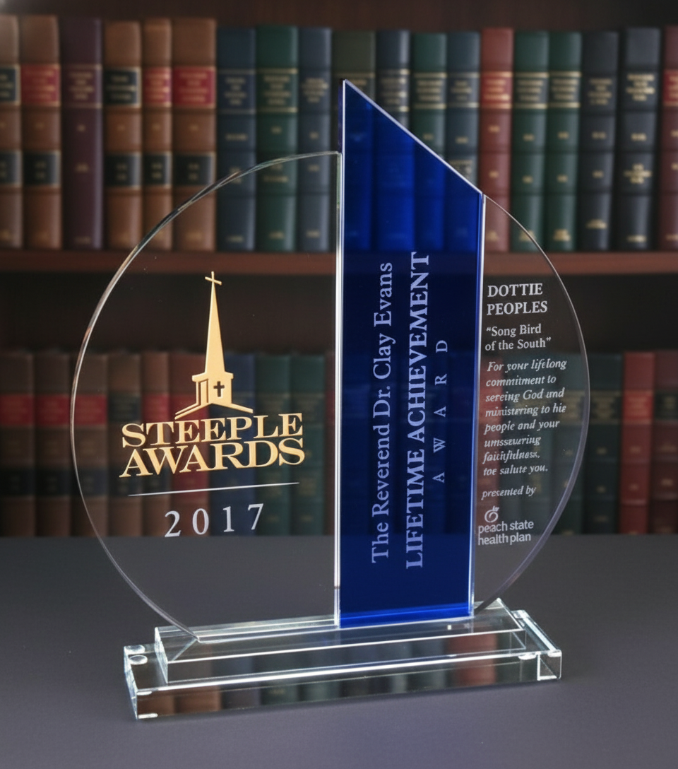 Elegant Steeple Awards trophy with blue and clear sections by Specialty Engraving in front of bookshelf.