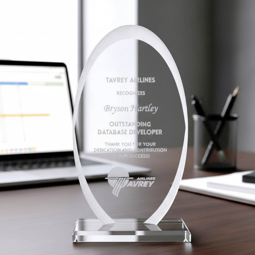 Glass award with frosted edges on a desk with a laptop in the background