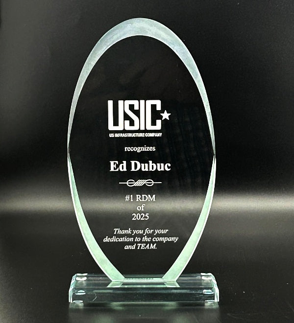 Glass award with beveled edges and sand etch engraved text on a black background