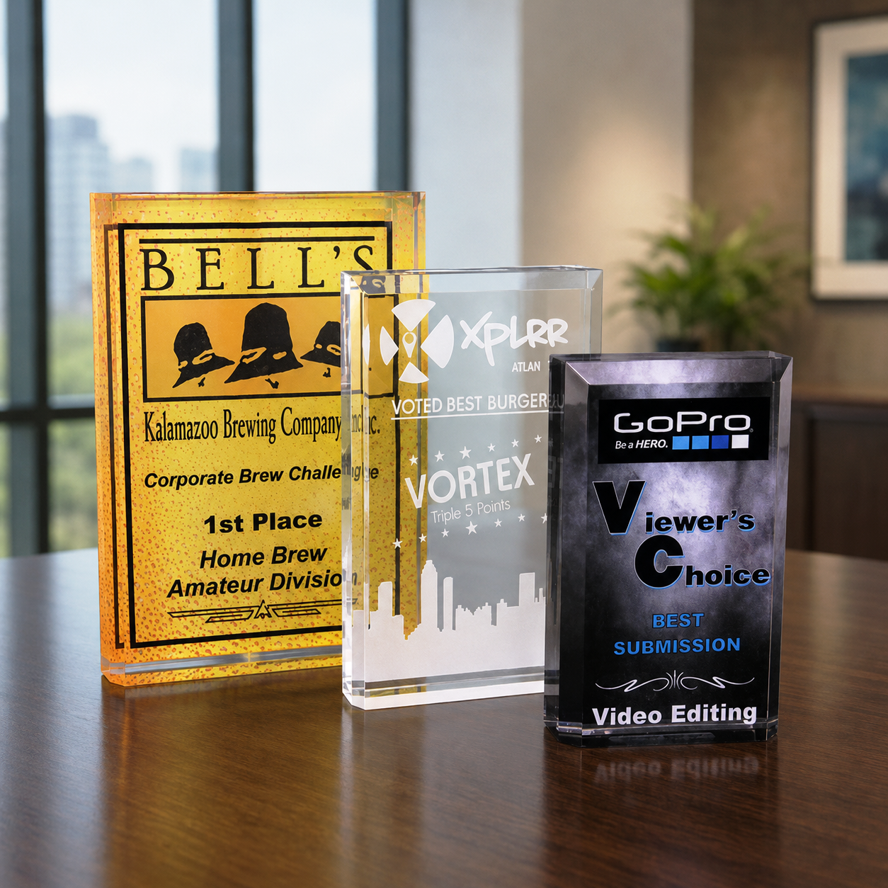 Three custom acrylic awards with engraved text and logos.