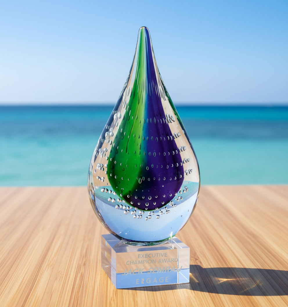 Crystal Glass award with green and purple interior on a wooden surface with ocean background