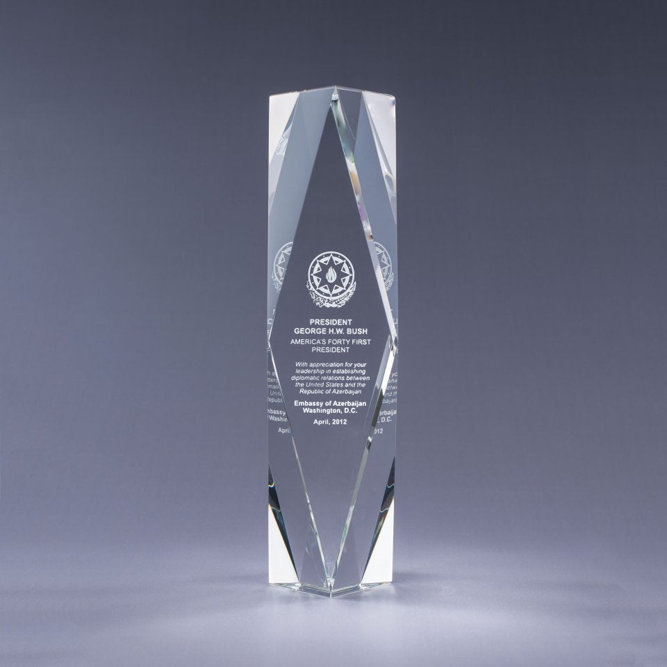 Clear crystal award with engraved text on a gray background