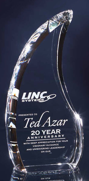 A crystal flame-shaped award with a reflective surface, featuring text that includes a corporate logo.