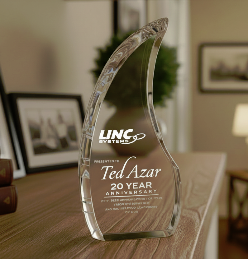 Crystal award with engrave logo and '20 Year Anniversary' text on a wooden surface.