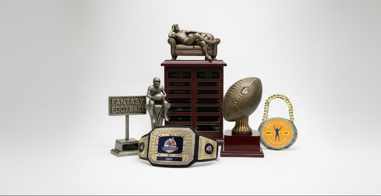 Collection of fantasy football trophies including a championship belt, football, and other decorative items on a white background.